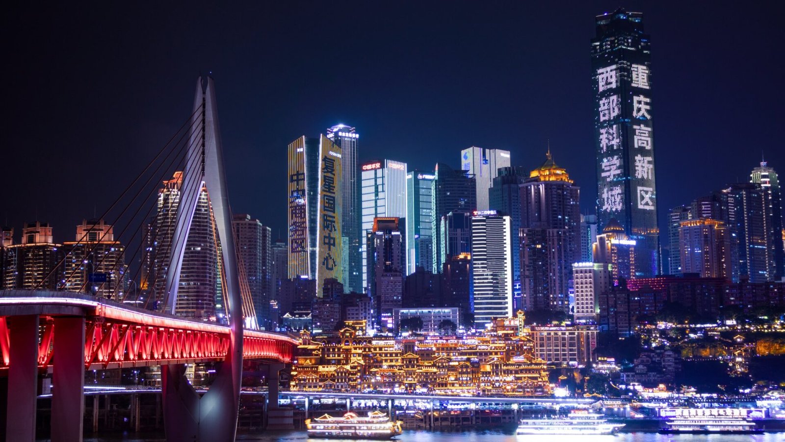 Rascacielos iluminados de Chongqing sobre el río Yangtsé, con el complejo de Hongyadong y el puente en primer plano