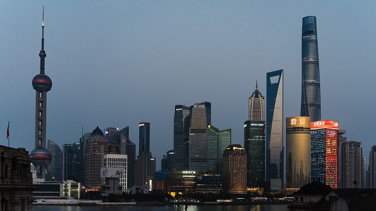Rascacielos de Pudong iluminados al anochecer vistos desde el Bund de Shanghái